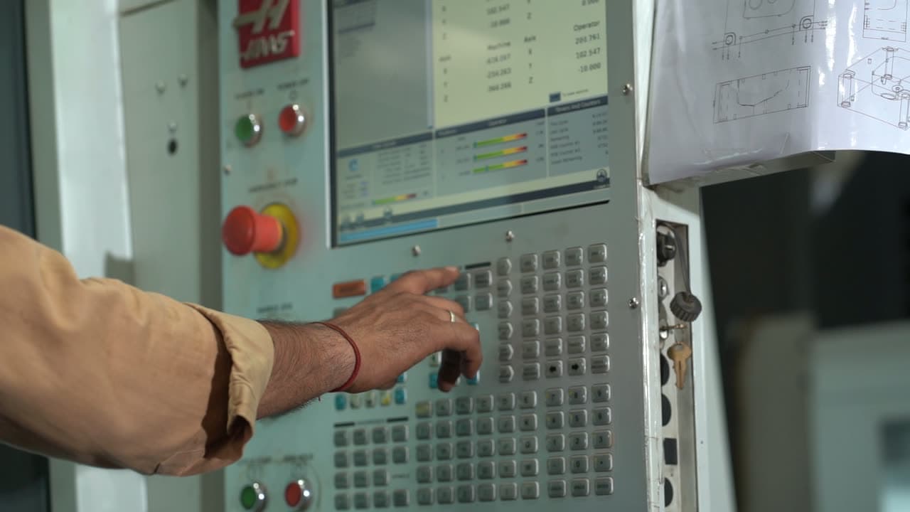An operator at the control panel of a CNC machine on the Bahadurgarh shop floor